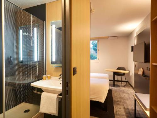 a hotel room with a bathroom with a bed and a sink at ibis Le Mans Est Pontlieue in Le Mans