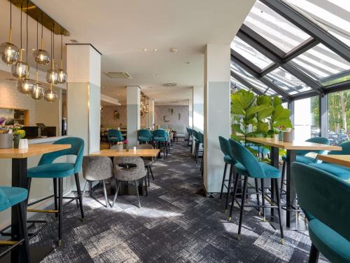 a restaurant with blue chairs and tables and windows at Mercure Hotel Köln West in Cologne