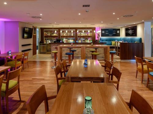 a restaurant with wooden tables and chairs and a bar at Mercure Hotel Köln West in Cologne