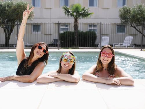 three girls in a swimming pool wearing sunglasses at ibis Aix en Provence in Aix-en-Provence