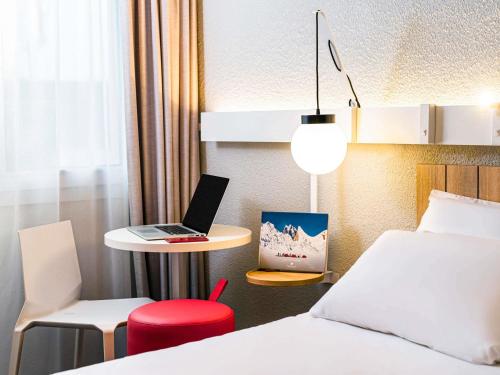 a hotel room with a bed and a laptop on a table at ibis Saint Rambert d'Albon in Saint-Rambert-dʼAlbon