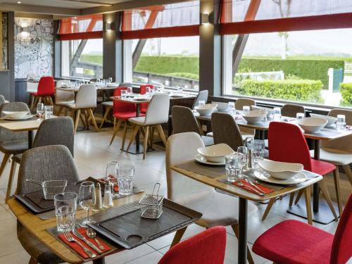 a restaurant with tables and chairs and windows at ibis Saint Rambert d'Albon in Saint-Rambert-dʼAlbon
