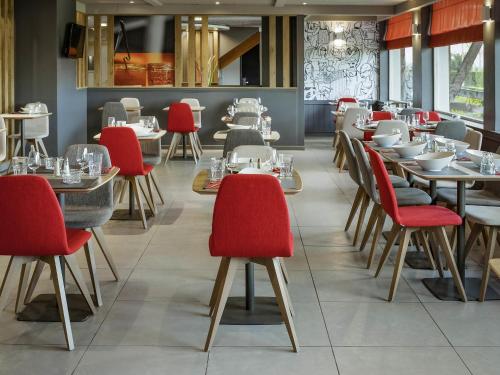 a dining room with tables and red chairs at ibis Saint Rambert d'Albon in Saint-Rambert-dʼAlbon