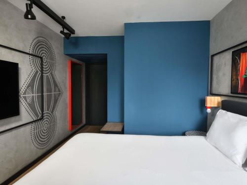 a bedroom with a white bed and a blue wall at Ibis Styles Abidjan Plateau in Abidjan