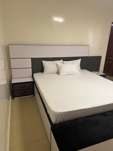 a bed with white sheets and pillows in a room at Résidence Dëkando in Malika