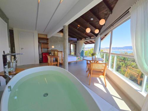 eine Badewanne in einem Raum mit einem großen Fenster in der Unterkunft Refúgio da Lagoinha - Centro de Bombinhas in Bombinhas