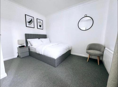 a bedroom with a bed and a chair and a mirror at Raflowhomeslondon in North Woolwich
