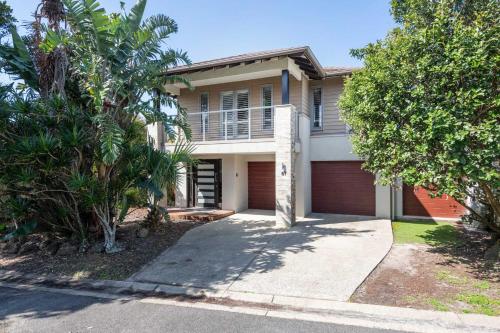 a house with a garage and palm trees at La Luna - Oceanstays in Lennox Head