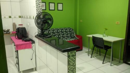 a green room with a fan and a table and chairs at Apartamento aconchegante in Marabá