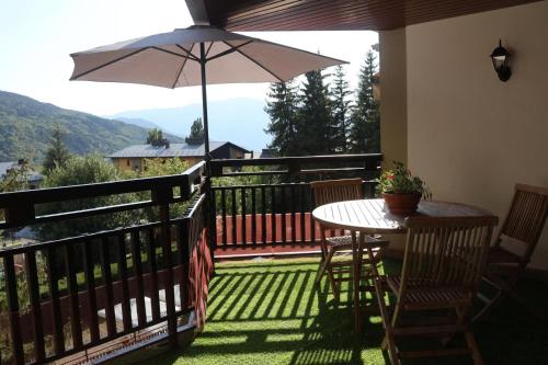 a balcony with a table and an umbrella at Con terraza y vistas a la montaña in Cerler