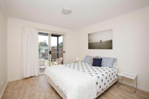 a white bedroom with a bed and a window at Beach holiday in Tomakin