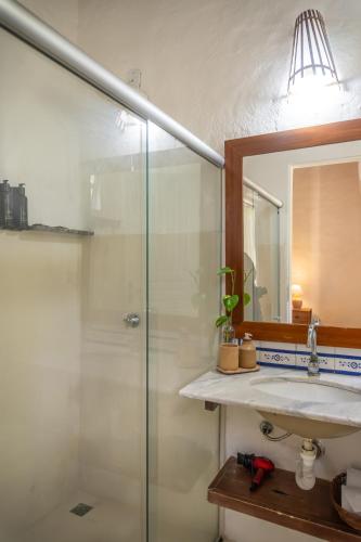 a bathroom with a shower and a sink and a mirror at POUSADA CARMELITHA in Trancoso