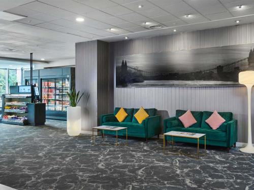 a lobby with green couches and colorful pillows at Novotel London West in London