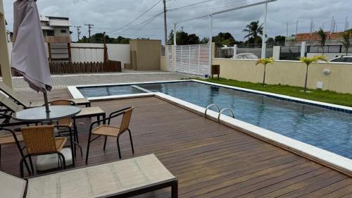 a deck with a table and chairs next to a swimming pool at Casa em Village Barra do Jacuipe in Camaçari