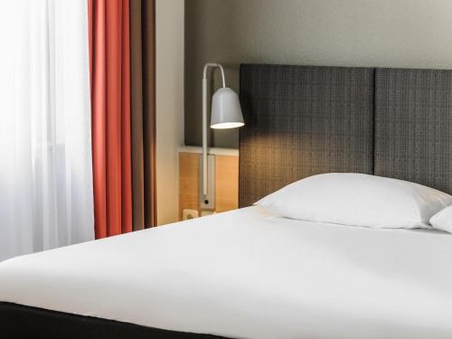 a bedroom with a white bed and a lamp at ibis Bremen City in Bremen
