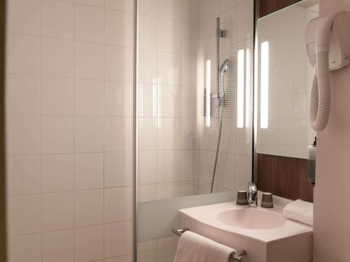 a white bathroom with a sink and a shower at IBIS STYLES Rouen Parc Expos Zenith in Saint-Étienne-du-Rouvray