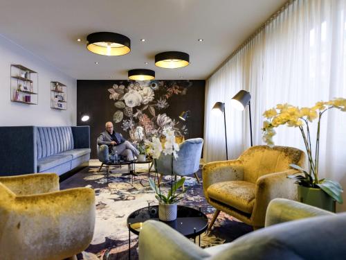 a man sitting in a chair in a living room at Mercure Hotel Duisburg City in Duisburg