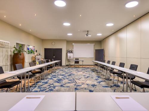 a conference room with tables and chairs and a whiteboard at Mercure Hotel Duisburg City in Duisburg