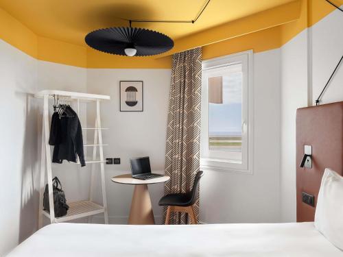 a bedroom with a bed and a table and a window at ibis Nice Aéroport Promenade des Anglais in Nice