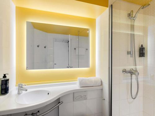 a bathroom with a sink and a shower with a mirror at ibis Nice Aéroport Promenade des Anglais in Nice