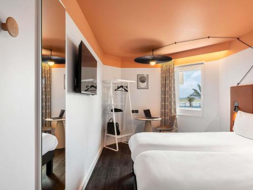 a hotel room with two beds and a desk at ibis Nice Aéroport Promenade des Anglais in Nice