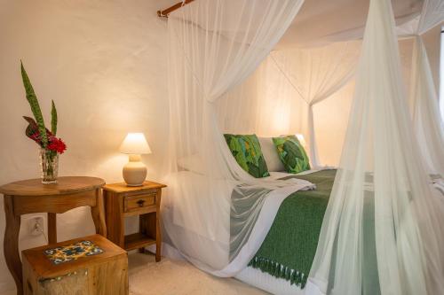 a bedroom with a canopy bed and a table with a lamp at POUSADA CARMELITHA in Trancoso