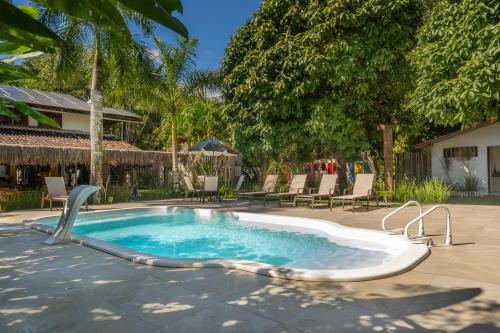 a swimming pool in a yard with chairs and trees at POUSADA CARMELITHA in Trancoso