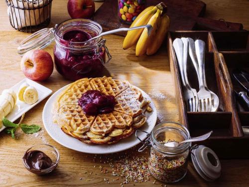 a table with a plate of waffles with syrup and fruit at ibis Metz Centre Gare in Metz