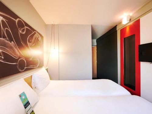 a hotel room with two beds and a tv at ibis Lyon Gerland Musée des Confluences in Lyon