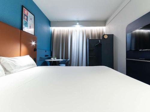 a hotel room with a large bed and a table at ibis Lyon Nord in Dardilly