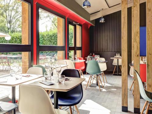 a restaurant with tables and chairs and windows at ibis Lyon Nord in Dardilly