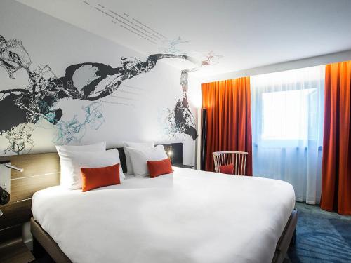 a bedroom with a large white bed with orange curtains at Novotel Paris Les Halles in Paris