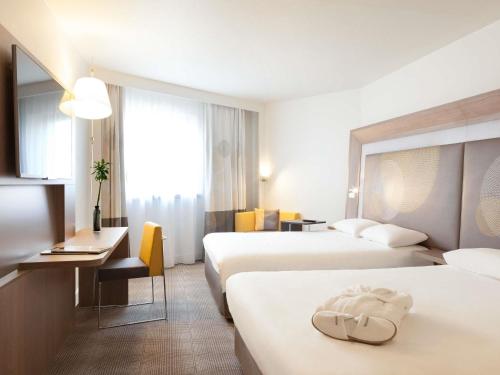 a hotel room with two beds and a desk at Novotel Paris Les Halles in Paris