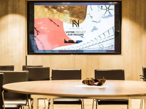 a meeting room with a table and a projection screen at Novotel Paris Les Halles in Paris