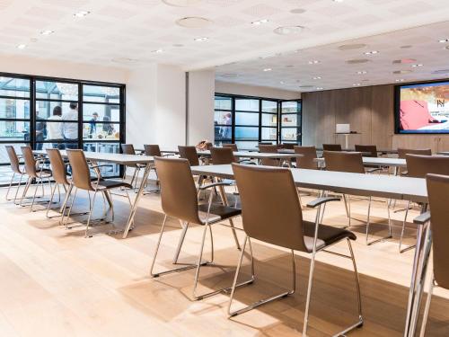 a conference room with tables and chairs and a projection screen at Novotel Paris Les Halles in Paris