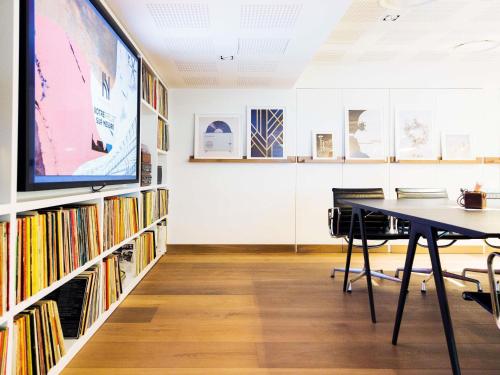a room with a table and a tv and books at Novotel Paris Les Halles in Paris