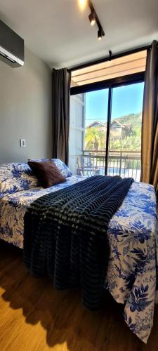 um quarto com uma cama e uma janela grande em Pousada Ecoblue Container em Palhoça