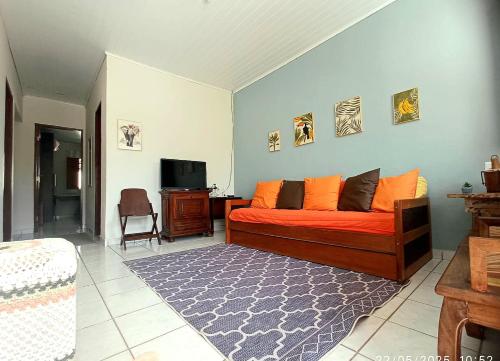 a bedroom with a bed with orange pillows and a television at CASA DA PRAÇA Ibicoara - a melhor hospedagem in Ibicoara
