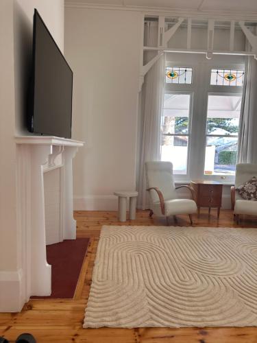 a living room with a flat screen tv on a fireplace at Beach Bungalow Henley - 4 minute walk to the Beach in Henley Beach