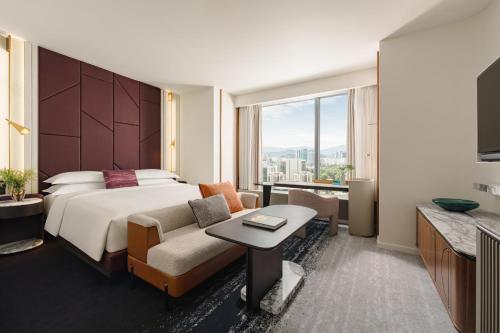 a hotel room with a bed and a couch and a tv at Kimpton Naluria Kuala Lumpur by IHG in Kuala Lumpur