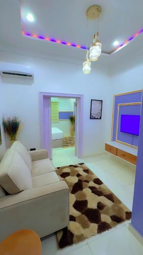 a living room with a white couch and a brown rug at Amia Gold Luxury Apartments in Abuja