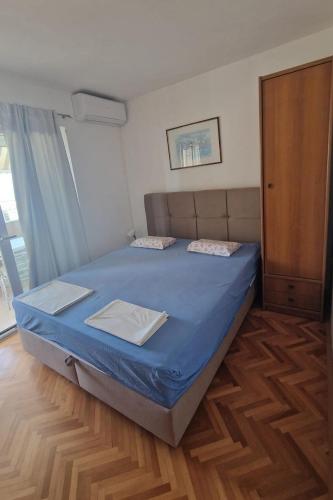a bedroom with a bed with blue sheets and a window at Apartments by the sea Podgora, Makarska - 2615 in Podgora