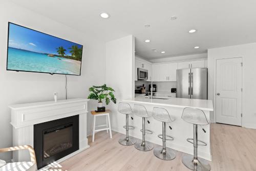 a white kitchen with a fireplace and a tv on the wall at Brand-New 3BR-3BA Family Home in Little River - All King Beds Minutes to NMB & ICW in Cherry Grove Beach