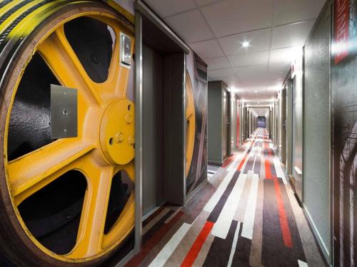 a long hallway with yellow wheels on the wall at ibis Deauville Centre in Deauville