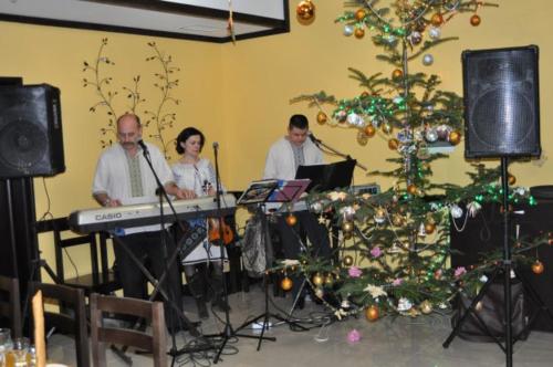 um grupo de pessoas a tocar música numa sala com uma árvore de Natal em Sribni Rosy em Mykulychyn