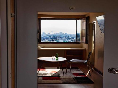a table and chair in a room with a window at Ibis Wien Mariahilf in Vienna