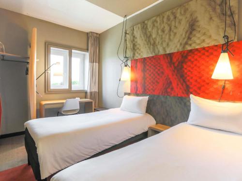 a hotel room with two beds and two lamps at Ibis Saint Étienne - La Terrasse in Saint-Étienne