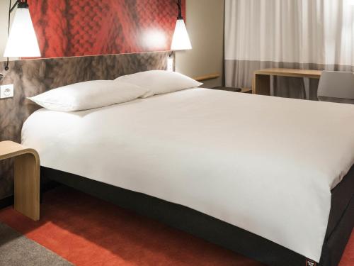 a large white bed in a hotel room at Ibis Saint Étienne - La Terrasse in Saint-Étienne