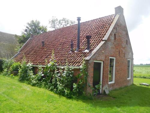 an old brick house with a green yard at Logementen Jannum in Burdaard