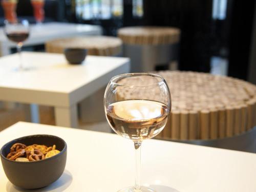 a glass of wine and a bowl of food on a table at Ibis Saint Étienne - La Terrasse in Saint-Étienne
